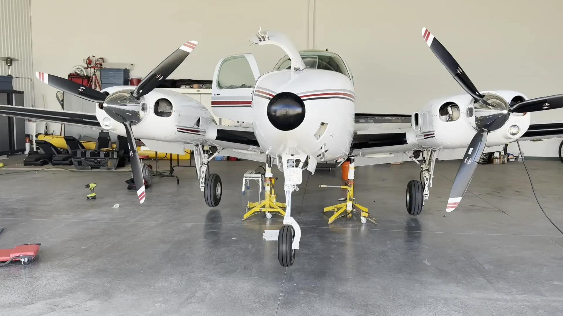 Beechcraft Baron on jacks in a hangar during an annual inspection, nose baggage door open